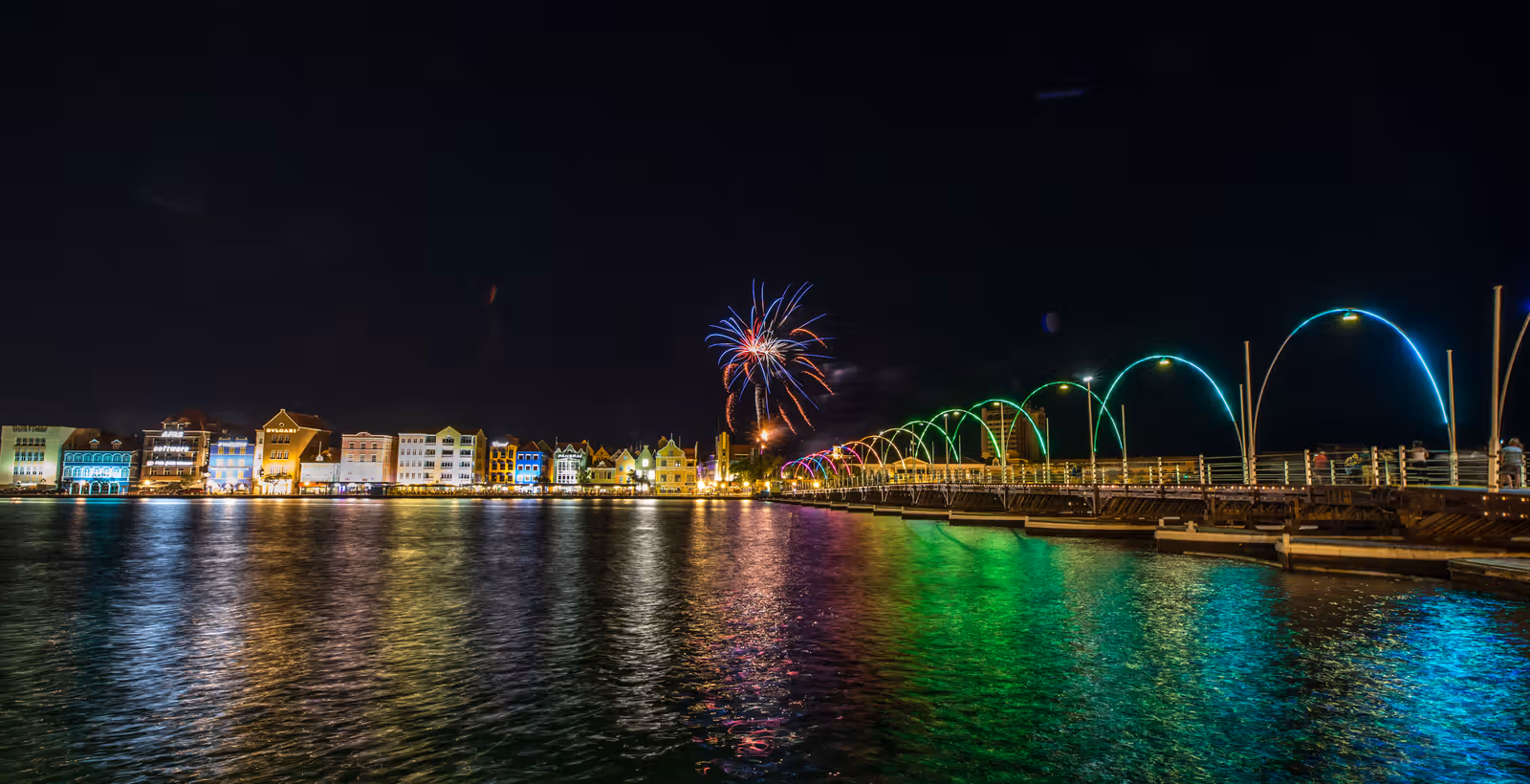 Verlichte voetgangersbrug en kade bij nacht