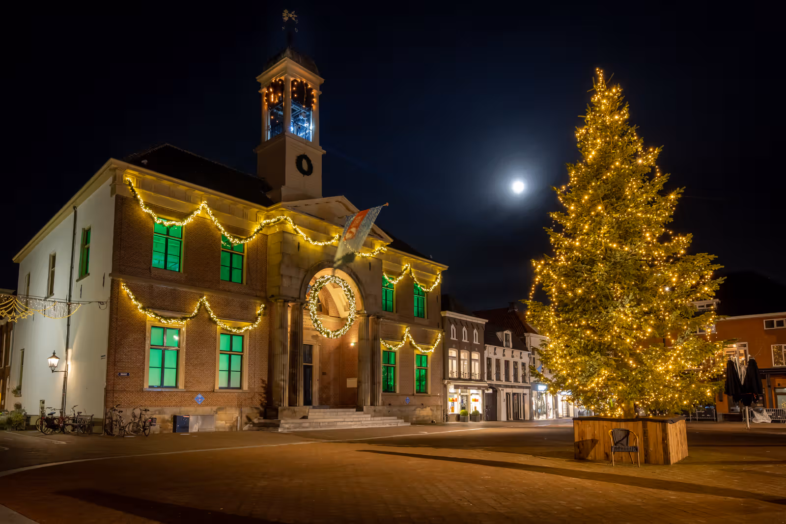 Verlicht historisch gebouw met kerstboom