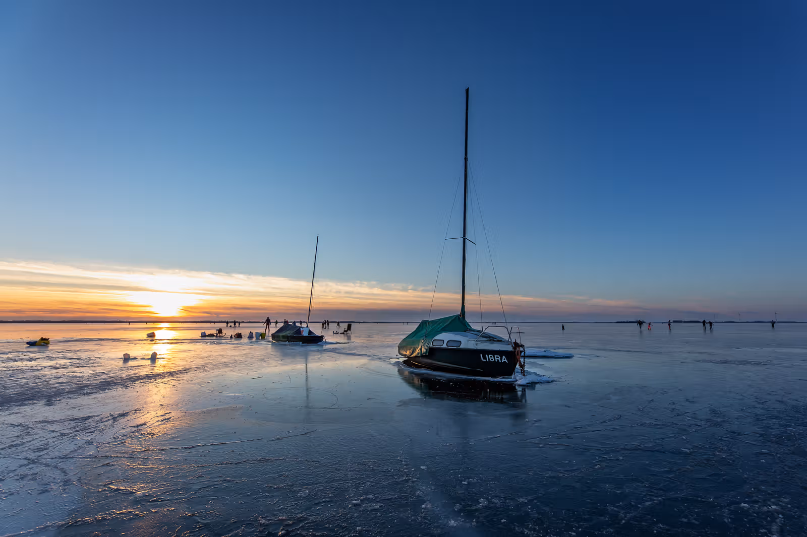 Zeilboot op ijs bij zonsondergang