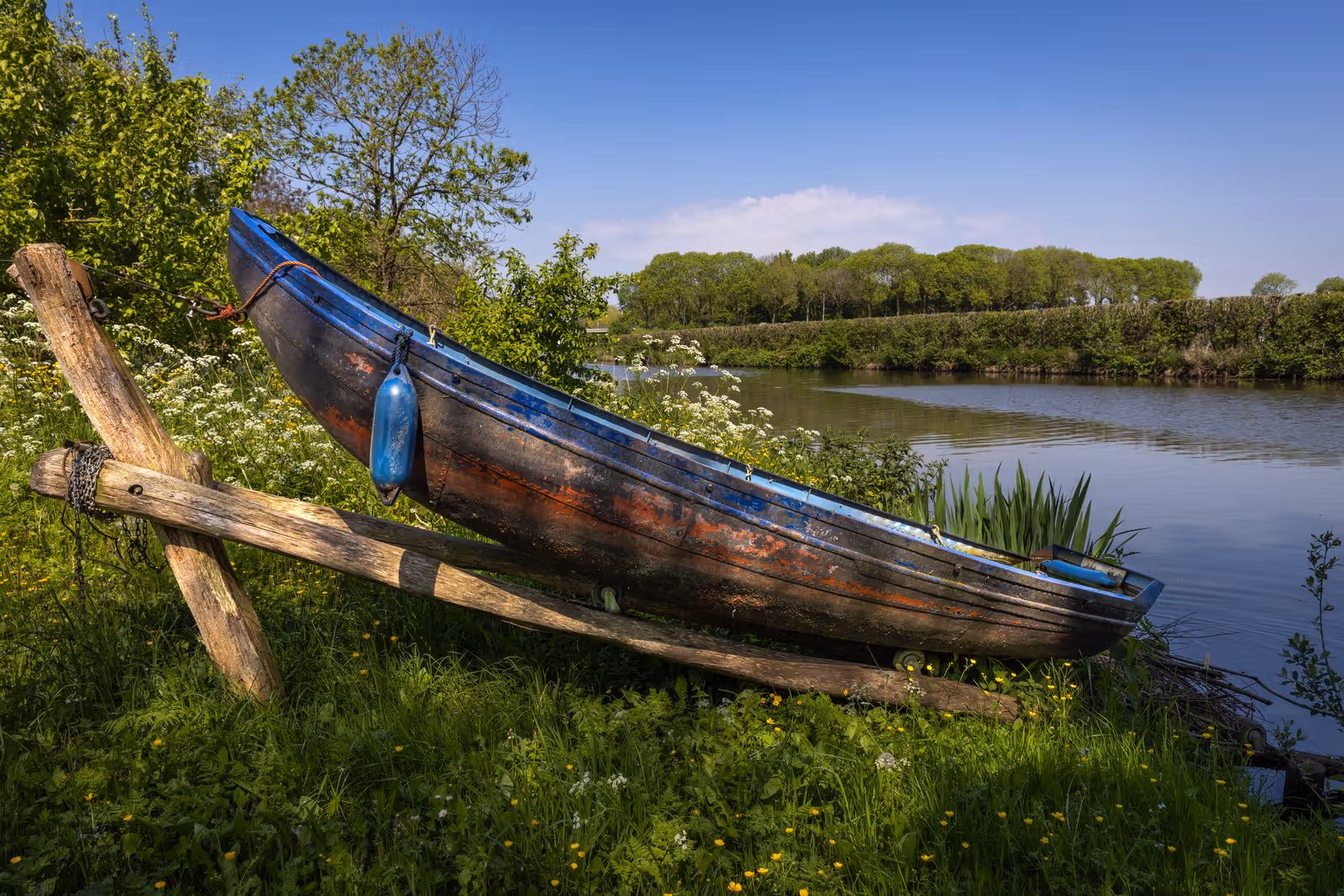 Blauwe roeiboot aan oever